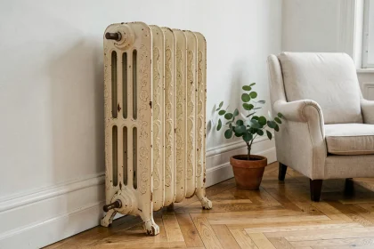 Radiateur en fonte à pieds design avec motifs floraux en relief dans un salon haussmannien au parquet en point de Hongrie