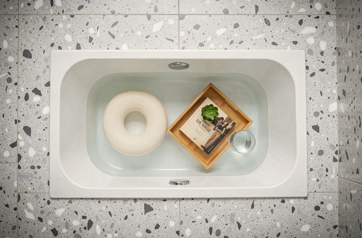 Vue en plongée d'une baignoire encastrée avec un faible niveau d'eau et accessoires écologiques, représentant le confort durable et l'économie d'eau